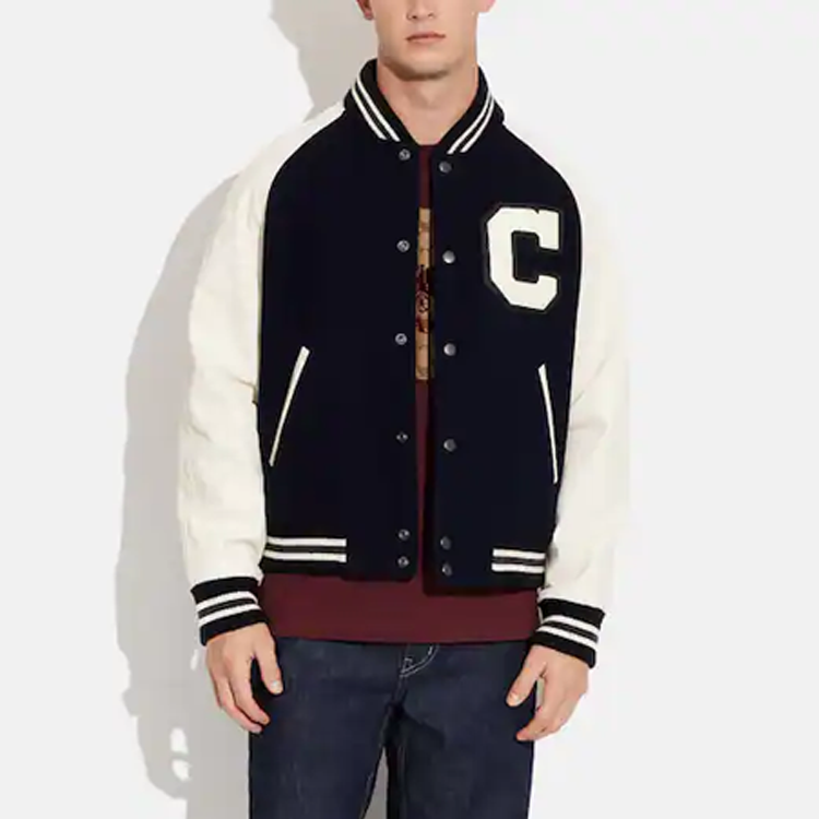 Lookbook 코치 SS23 블랙 래글런 슬리브 바시티 재킷 - 대비되는 레터 패치 디테일. CF802-VC8